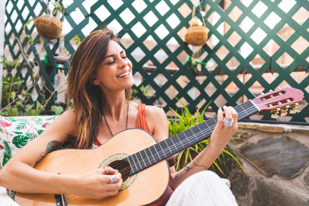 hermosa-mujer-tocando-guitarra-al-aire-libre_102573-441